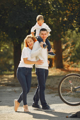 Family in a park. People with a bicycle. Parents with little son.