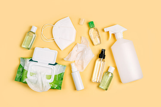 White medical masks and respirators with antibacterial wet wipes, disinfection spray and hand sanitizer on yellow background. Personal hygiene product for protection virus, flu, coronavirus, COVID-19