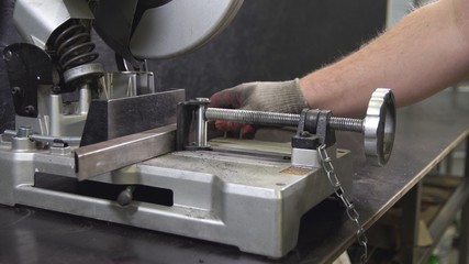 Working man with big saw cutting metal. Grinding in steel manufactory.