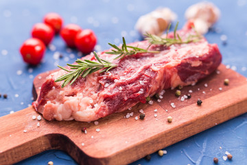 Fresh raw meat for steak on wooden cutting board.