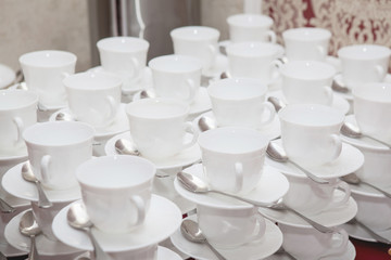 White porcelain cups and saucers on a table set on top of each other in a row