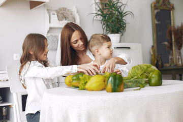 Fototapeta premium Family in a kitchen. Beautiful mother with children. Lady in white blouse.