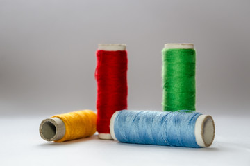 Composition of four multi-colored threads, with a focus on blue and yellow.