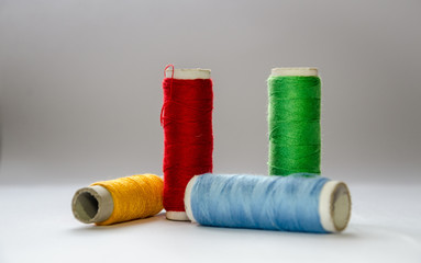 Composition of four multi-colored threads, with a focus on red and green.