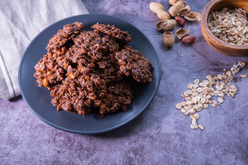 Healthy oatmeal cookies on a grey plate with peanuts and oat on concrete background. Close up view.