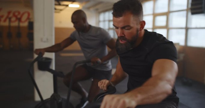 Two fit young men riding stationary bikes during a
cardio workout session in a gym
