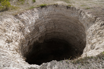 Round karst sinkhole, formed above abandoned limestone mine. Total diameter about 15 ft, depth...