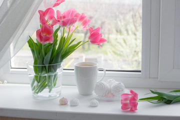 postcard good morning. Still life : a Cup of tea, a bouquet of pink tulips, marshmallows on a light background near the window.