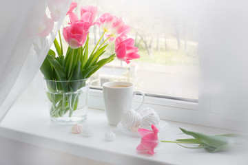 postcard good morning. Still life : a Cup of tea, a bouquet of pink tulips, marshmallows on a light background near the window.