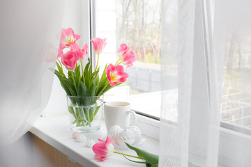 postcard good morning. Still life : a Cup of tea, a bouquet of pink tulips, marshmallows on a light background near the window.