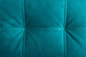 Closeup of blue cushion with thread stitches. Velvet texture as a background.Empty space