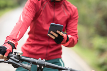 Cyclist use smartphone for navigation when riding mountain bike on forest trail