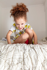 Funny red-haired girl having fun, making funny silly silly funny faces gesture, having fun in bed indoors