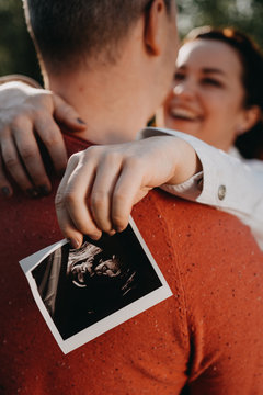 Pregnant couple with photo of kid, white, baby on board photo session