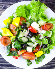Vegetable salad cucumbers peppers cheese olives on a white plate close-up	