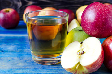 apples red and green and transparent glass of Apple juice on a wooden background side view	