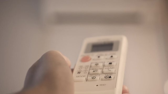 4K Close up hand switch on air condition by remote control . Concept of energy and power saving.
