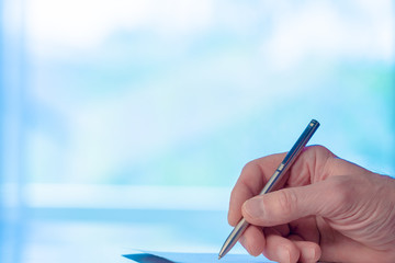 Man signs a document form with a ballpoint pen in the office