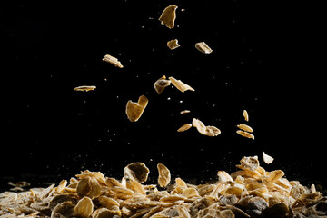 Whole oats being poured onto counter, oatmeal on a black background