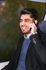 Portrait of muslim man talking on phone in train
