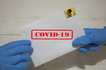 Ludzkie ręce w rękawicach ochronnych z listem, który może zawierać wirusa COVID-19. Przesyłki...