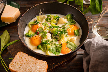 eggs with  broccoli, cheese, spinach in a pan on a dark wooden background, protein healthy Breakfast