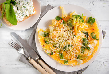 omelet with cheese, broccoli, spinach on a white plate, sandwich with cheese and greens on a white
