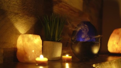 4k, Oil essentials next to electric diffuser lamp, candles on wooden table in room. Aromatherapy.