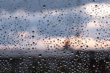 Naklejka na ściany i meble Horizontal frame of rain drops on window glass at sunset in the city