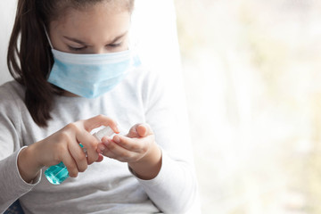 Cute child girl in a mask cleaning hands with antiseptic. Pandemic. Krantin. Covid 19