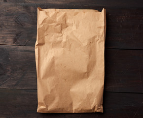 open brown paper bag for food packaging on a brown wooden background