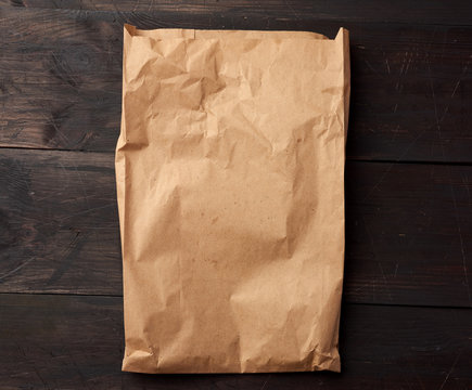 Open Brown Paper Bag For Food Packaging On A Brown Wooden Background