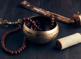 Tibetan singing copper bowl with a wooden clapper on a brown wooden table, objects for meditation...