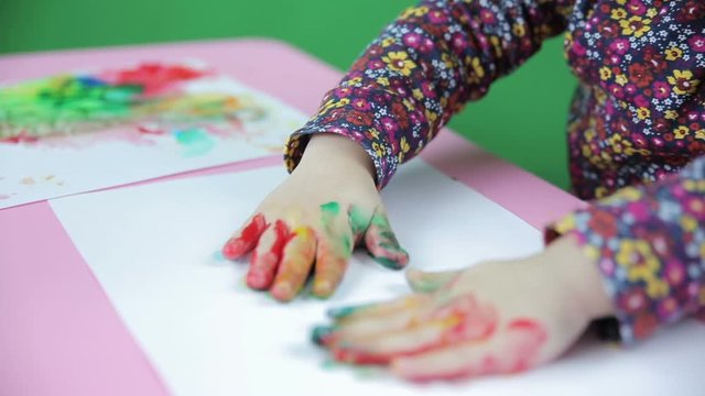 Hands dirty with paint and a girl and she drawing on a sheet of paper closer green screen