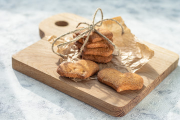 Heart-shaped gluten-free cornmeal cookies on wooden board and light background, horizontal