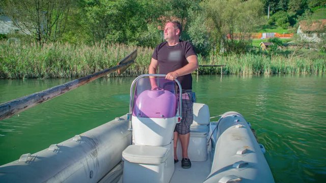 man pilot an inflatable boat on Drava river. Smiling and waving . Koroska