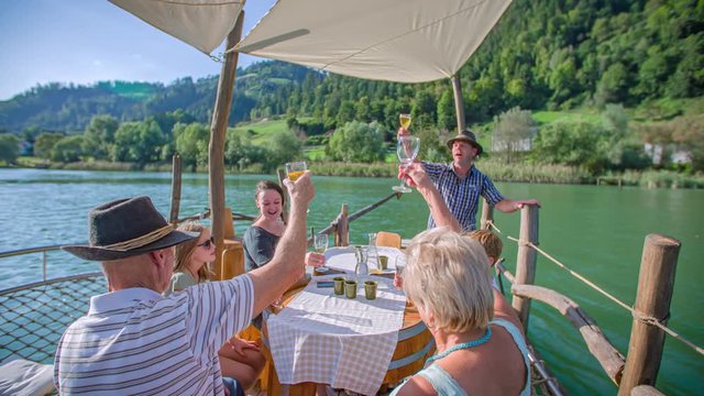 Slow motion of a Slovenian family having a toast while riding a traditional raft on Drava river