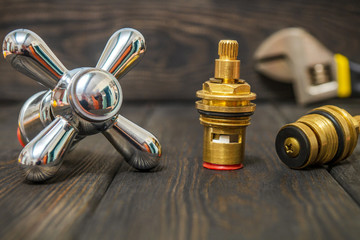 A cruciform hot and cold water main switch of spare parts on black wooden boards