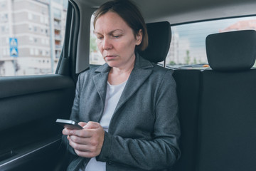Businesswoman text messaging on mobile phone in car