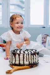 a little girl in a dress is preparing to blow out a candle on a birthday cake