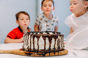 a little three-year-old girl blows out the candle on the cake