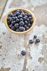 Image of blueberries in wooden bowl on rustic village table.