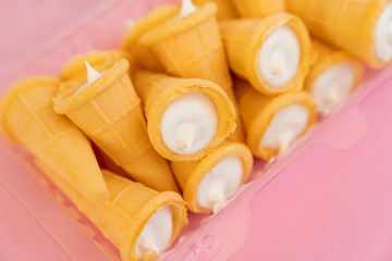 Vanilla cream in wafer cup on pink background. 