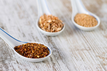 Spices and herbs in porcelain spoons over a wooden background