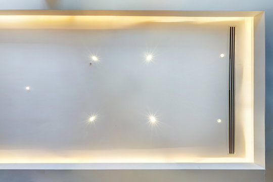 look up on suspended ceiling with halogen spots lamps and drywall construction with fire alarm sensor in empty room in apartment or house. Stretch ceiling