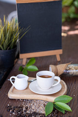 a white cub of coffee with a white cub of honey on wooden plate, background with wooden black board