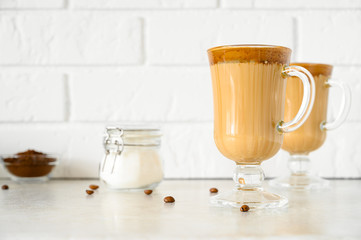 Korean Dalgona coffee in tall glass mugs. Trendy refreshment creamy whipped Macau coffee. Horizontal orientation, copy space. Light brick background.