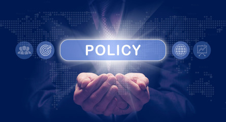 Businessmans cupped hands holding an Policy business concept on a computerised display.