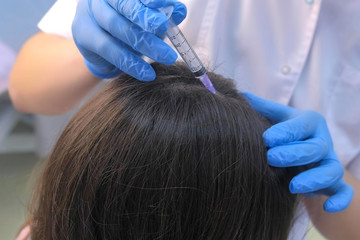 Naklejka premium Doctor trichologist making multiple injections mesotherapy in woman skin head for hair growth in cosmetology clinic, closeup hands view. Making treatment procedure to patient for hair cure.