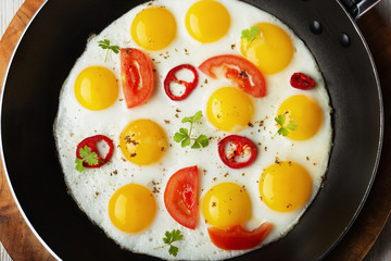 Fried eggs in iron pan with vegetables, close up